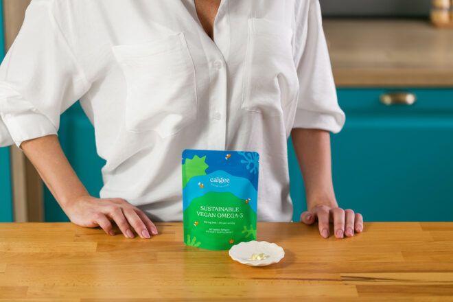 A person with a white shirt standing behind a Calgee Omega-3 package