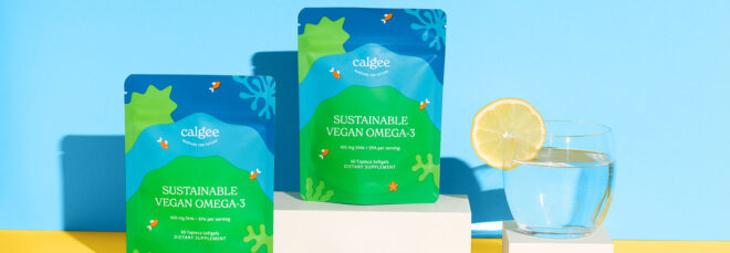 Two bags of Calgee Omega-3 and a glass of water with a lemon wedge on the lip