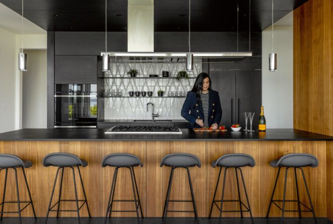 A person standing behind an island with bar stools
