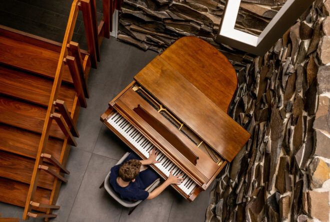 Looking below at a person playing on a brown wooden piano