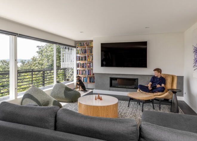 A person sitting on a chair beside their dog in a living room space