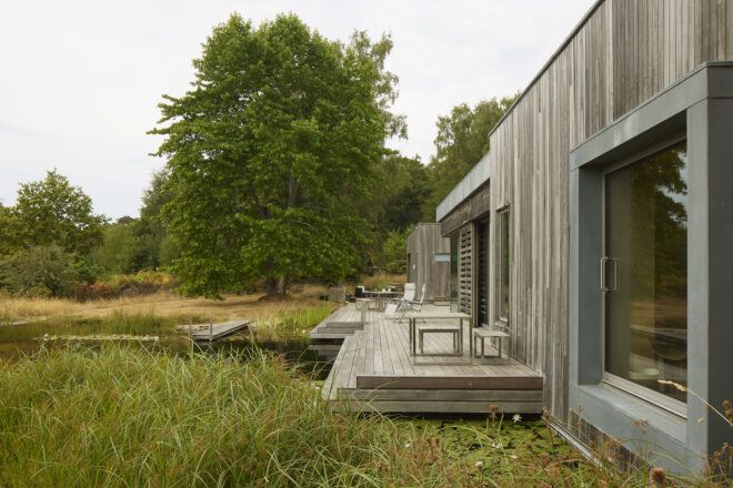 The side look of a wooden home with a front porch that leads to a water