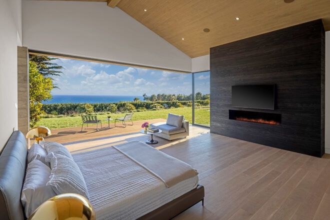 A bedroom with an open wall leading to an outdoor seating space