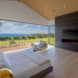 A bedroom with an open wall leading to an outdoor seating space