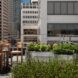 A rooftop seating area with planters overlooking skyscrapers
