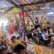 An interior of a bamboo structure filled with people sitting and standing facing the front
