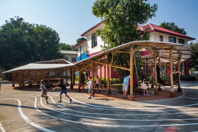 A shaded structure with people playing and standing underneath it