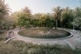 A circular pond surrounded by a walkway, trees and bushes