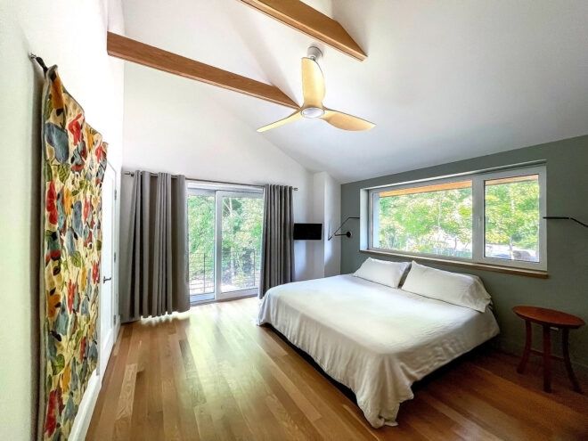 A bedroom with curtains covering a screen door