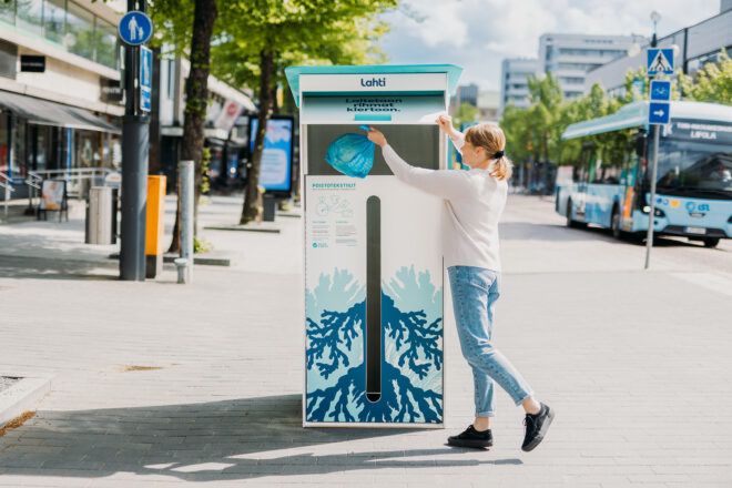 A person dropping a bag of clothes into a drop off bin